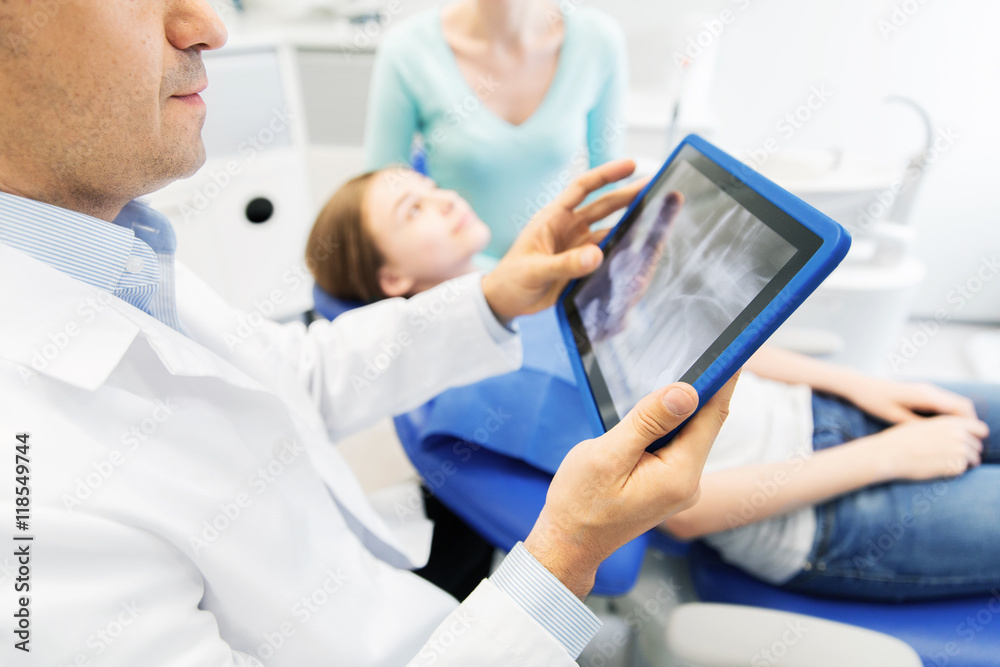 Obraz premium dentist with x-ray on tablet pc with patient girl