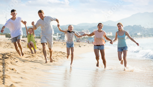 Family with kids happily running together on beach