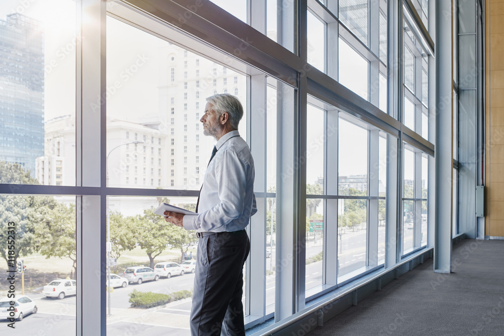 Businessman looking out of a big window Businessman looking out of a big window