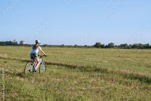 young woman riding bicycle in fields © serejkakovalev