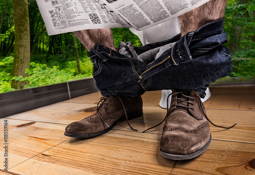 Adult male reading newspaper while sitting on the toilet seat