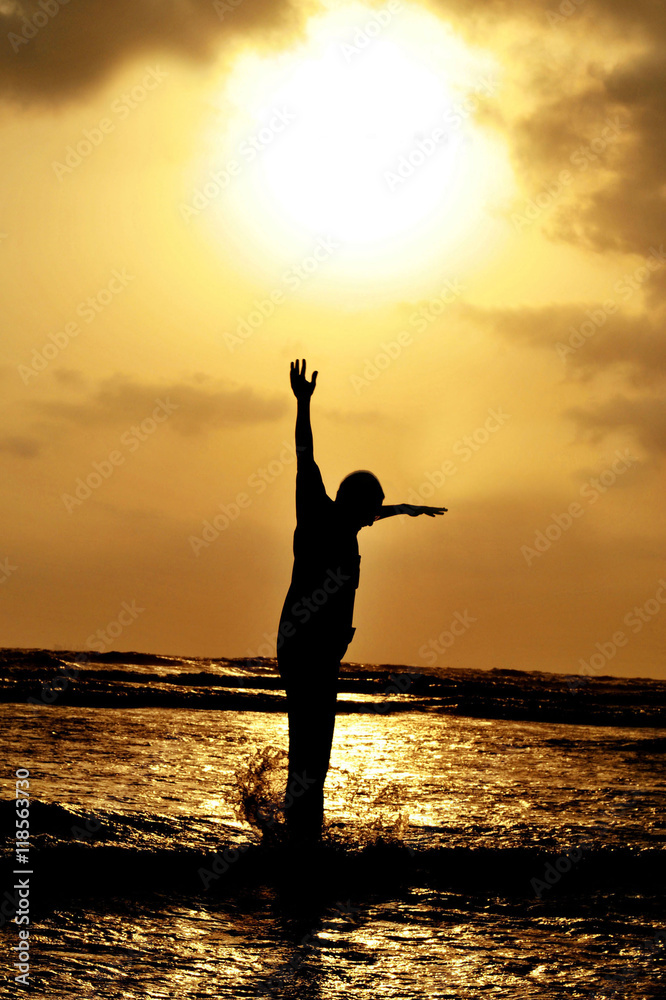 Fototapeta premium man jumping against setting sun on beach