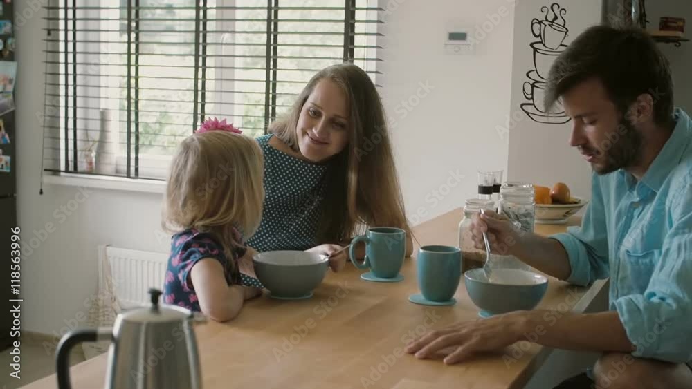 Mother is smiling at her daughter while having conversation with husband at the kitchen table. Slow mo, Steadicam shot Mother is smiling at her daughter while having conversation with husband at the kitchen table. Slow mo, Steadicam shot