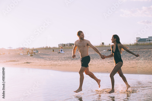 a couple is running on beach while the sun is set