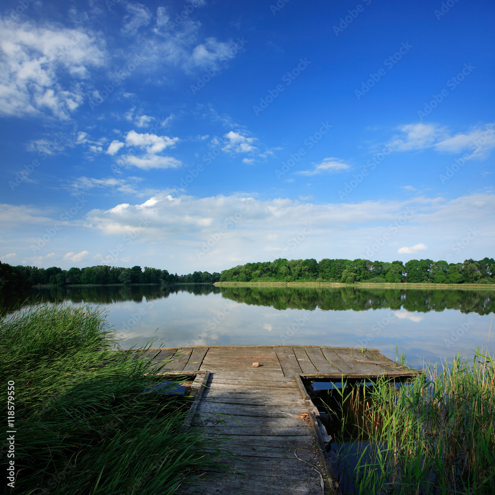 Fototapeta premium Old Wooden Pier on Lake under Blue Sky in Summer Landscape
