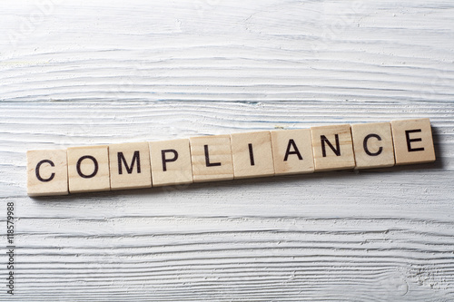Compliance word written on wood abc block at wooden background.
