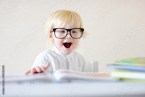 Little boy with eyeglasses reading book