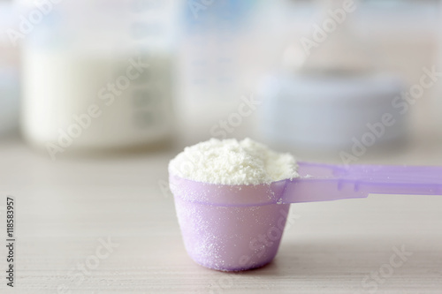 Baby milk formula in purple spoon on wooden background