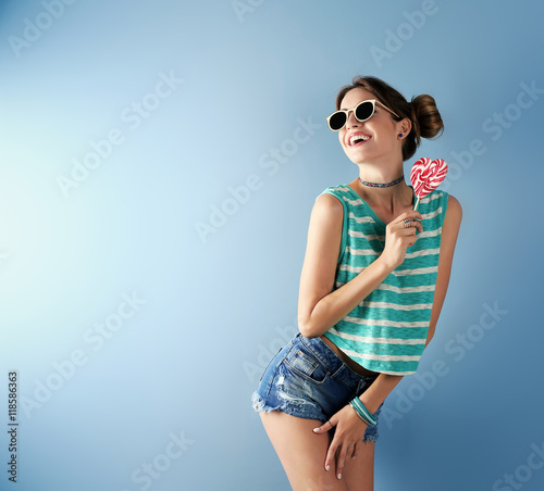Beautiful girl with candy on blue background