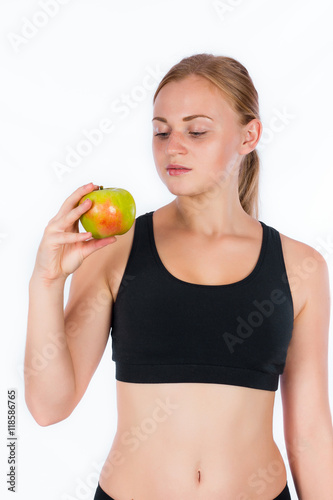 Beautiful young blonde woman with an apple in his hand. A young athletic woman holding a big green apple in her hand