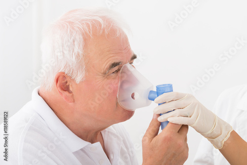 Man Using Oxygen Mask In Clinic