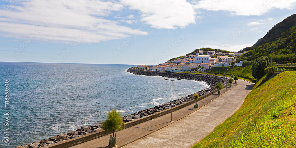 Atlantic Ocean coast and picturesque village at the mountain foot in Azores, Portugal. Church and village houses on Sao Miguel Island in Azores, Portugal.