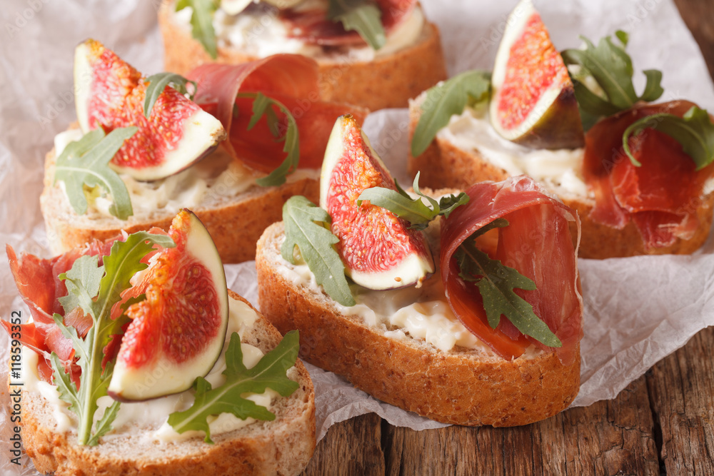 Healthy sandwiches with figs, prosciutto, arugula and cheese close-up. Horizontal
