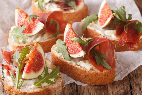 Healthy sandwiches with figs, prosciutto, arugula and cheese close-up. Horizontal 