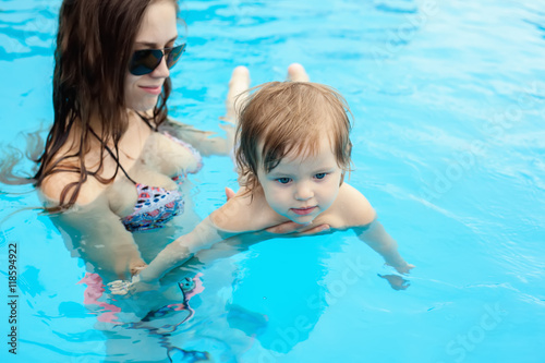Young mother with her little daughter in the pool