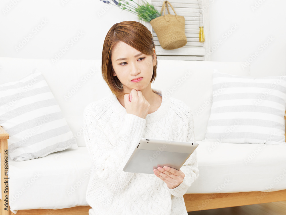 リビングでタブレットを使う女性 考える リビングでタブレットを使う女性 考える