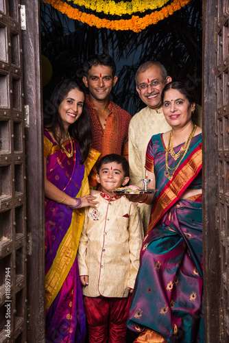 indian family group photo while entering house with puja thali at old antique door, gruha pravesh photo