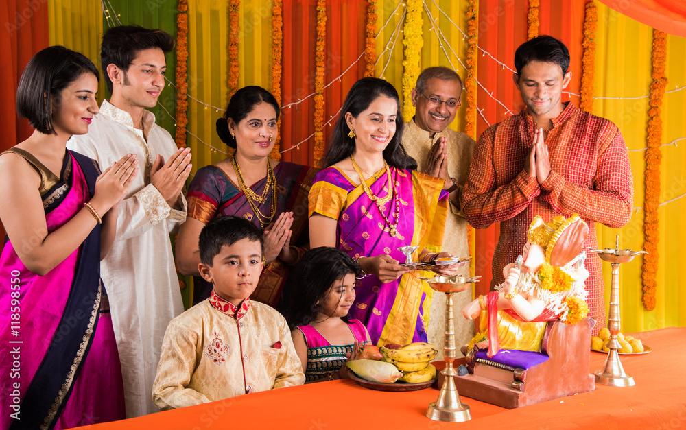 cheerful indian family celebrating or praying Lord Ganesh or ganpati