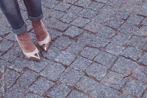 female legs in a beautiful peach high-heeled shoes with gold nose. close-up. on the granite pavement