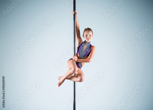 The strong and graceful young girl performing acrobatic exercises on pylon