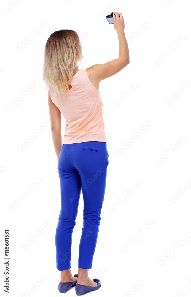 back view of standing young beautiful woman and using a mobile phone. girl watching. Rear view people collection. backside view of person. Isolated over white background. The blonde in a pink t back view of standing young beautiful woman and using a mobile phone. girl watching. Rear view people collection. backside view of person. Isolated over white background. The blonde in a pink t