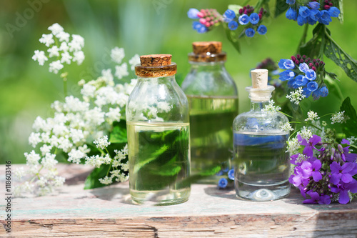 Essential aroma oil in bottles on wooden background outdoor.
