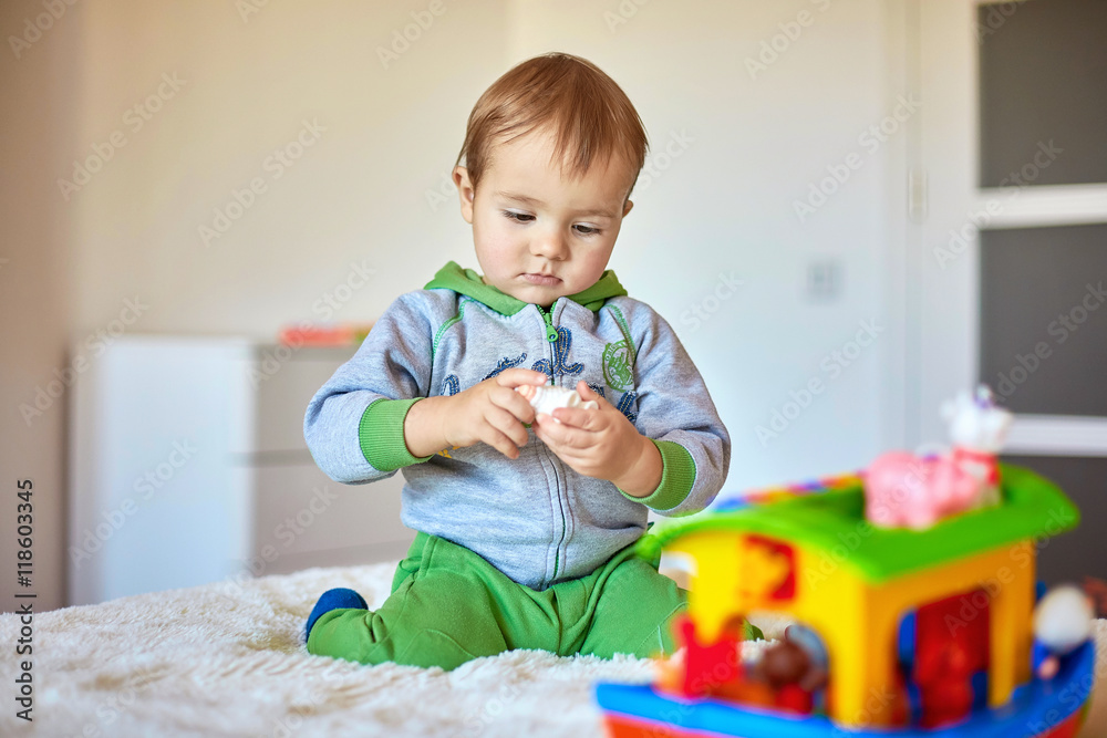 Lovely child plays with toy house on the bed Lovely child plays with toy house on the bed