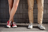 Close up of couple's legs in keds over grey wall.