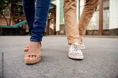 Close up of couple's legs in keds walking down street.