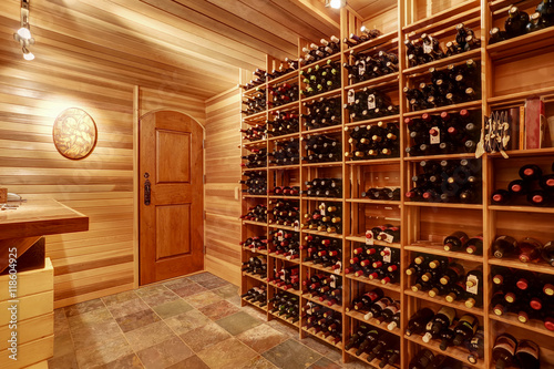 Bright home wine cellar with wooden storage units with bottles. photo