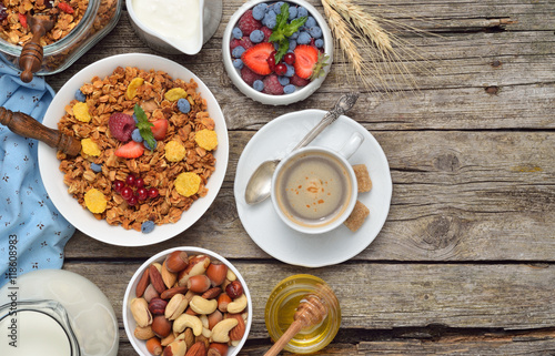 Ingredients for a healthy breakfast - berries, homemade granola, milk, dried fruits, nuts on wooden table. Copyspace background.Top view.