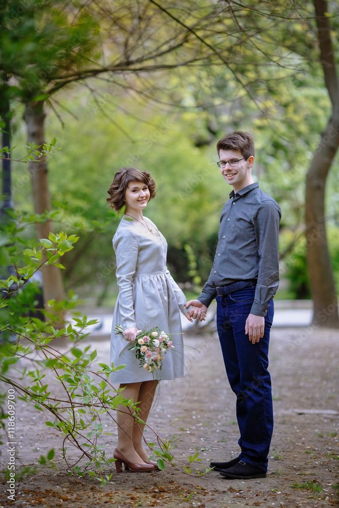 Fototapeta premium Young man and charming lady in grey dress pose in the park