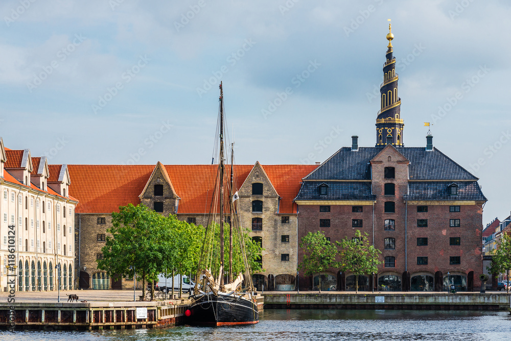 Church of Our Saviour spiel, scandinavian houses and sail ship on Christianshavn canal. Copenhagen, Denmark