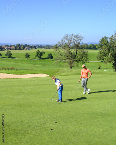 Golf-Trainer beobachtet den Putt des Nachwuchsspielers