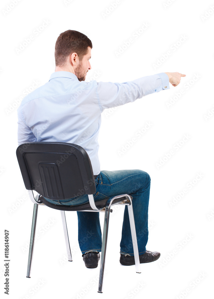 back view of young business man sitting on chair and pointing. Rear view people collection. Bearded businessman sitting on a chair and shows a finger forward. back view of young business man sitting on chair and pointing. Rear view people collection. Bearded businessman sitting on a chair and shows a finger forward.