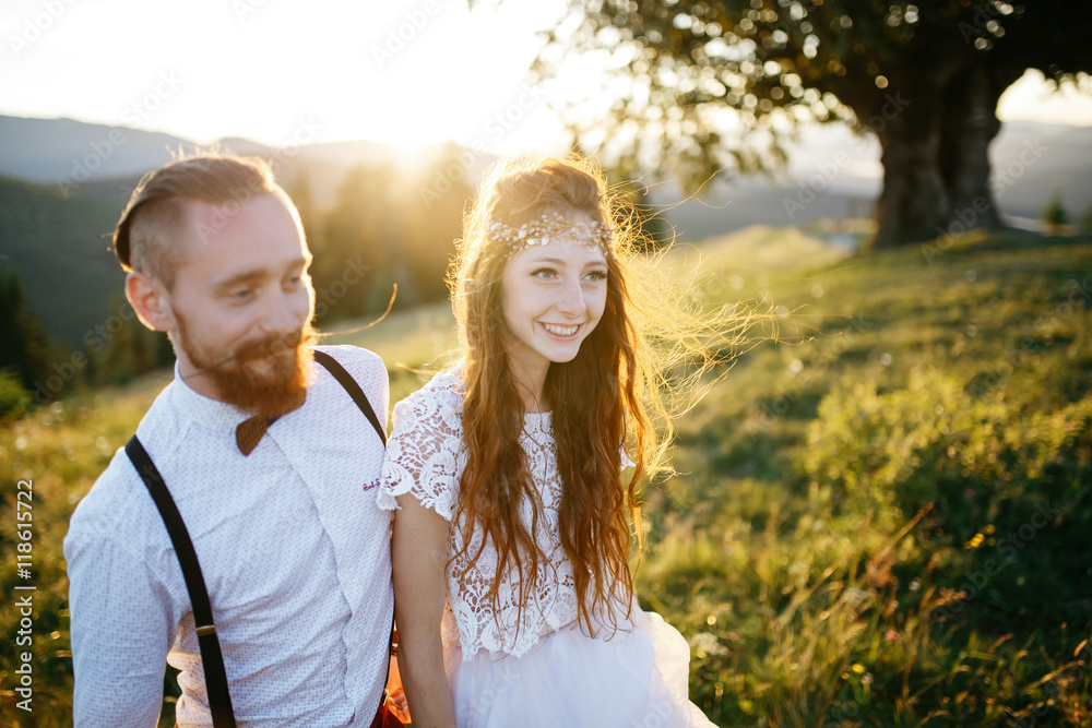 Beautiful bride in shining wreathe walks with red bearded groom