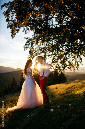 Sun shines through the gorgeous wedding coupel posing on the fie