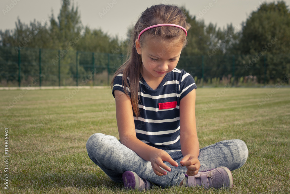 Dziewczynka siedząca na trawie - obrazy, fototapety, plakaty 