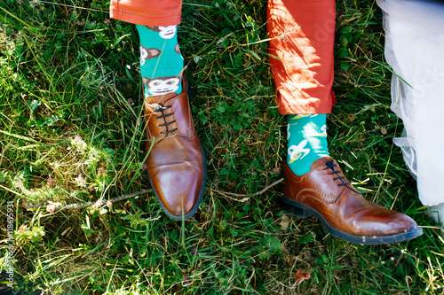 Man's feet in leather shoes and green socks lie over the lawn