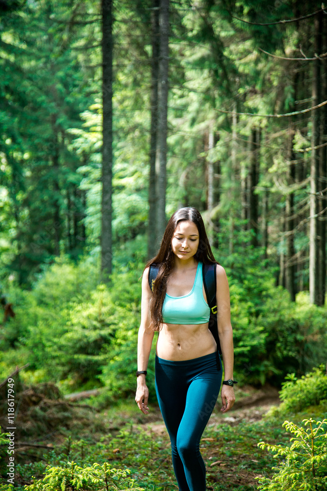 Young beautiful girl tourist with a Hiking backpack and a sports figure walking in the woods Young beautiful girl tourist with a Hiking backpack and a sports figure walking in the woods