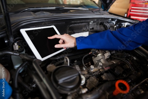 Mechanic using a digital tablet while servicing car engine