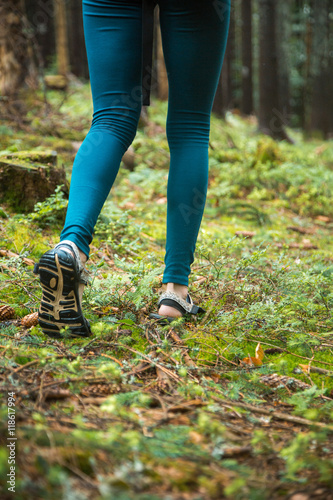 Young beautiful girl tourist athletic figure walks in the woods. Female legs walking on forest trail