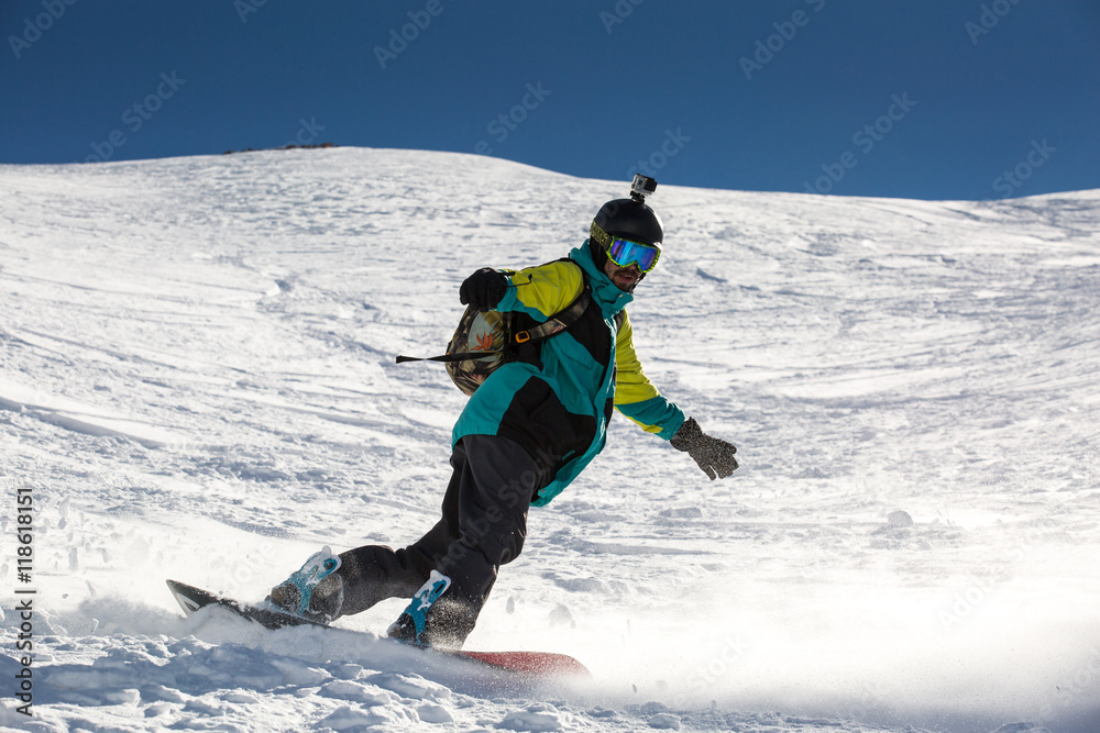 Man snowboarder snowboarding on fresh white snow on ski slope on Sunny winter day