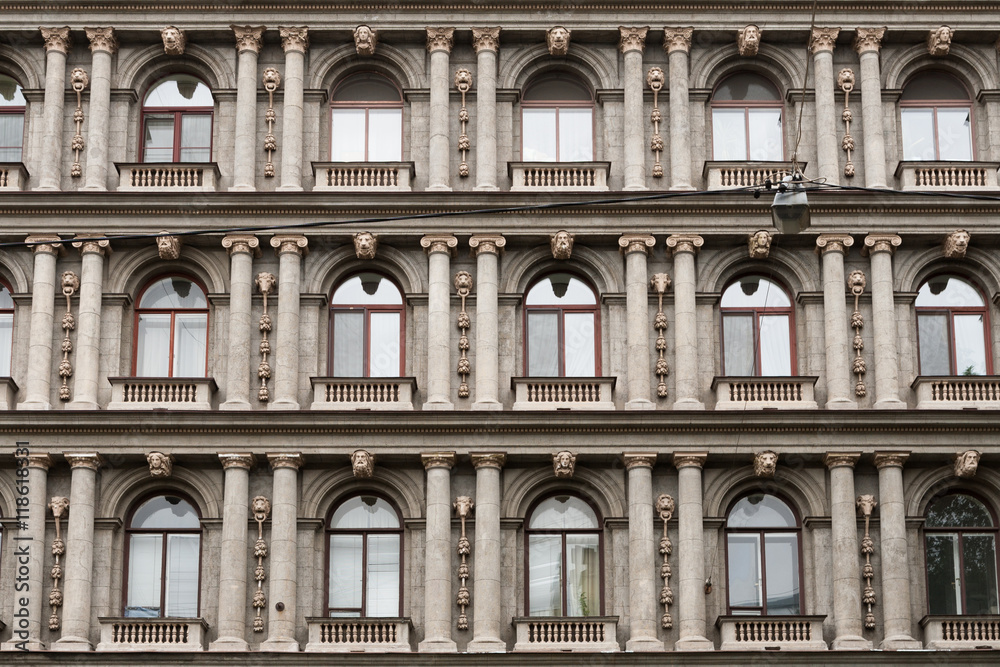 Detail of the facade of a multistory building in classical style with columns and windows.