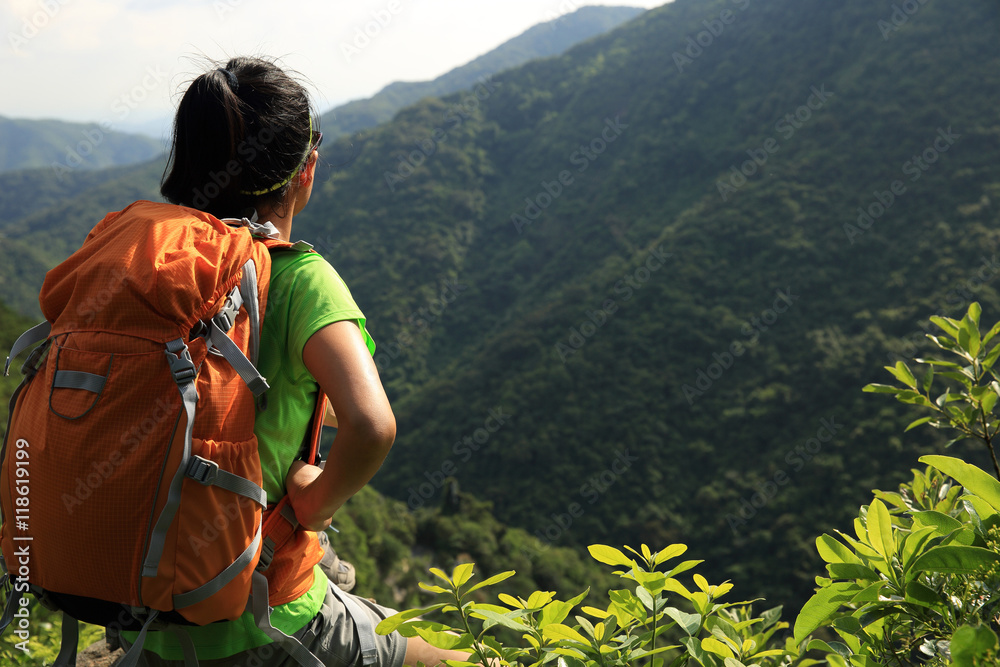 woman backpacker enjoy the view at mountain peak cliff