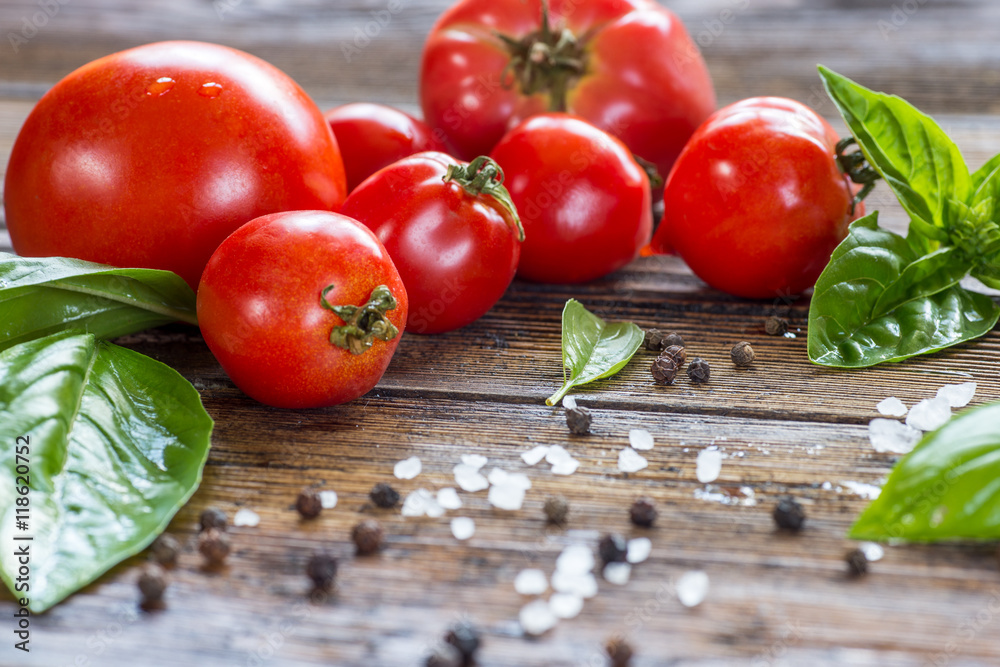 Tomatoes with basil in colander on wooden table background. Food Tomatoes with basil in colander on wooden table background. Food