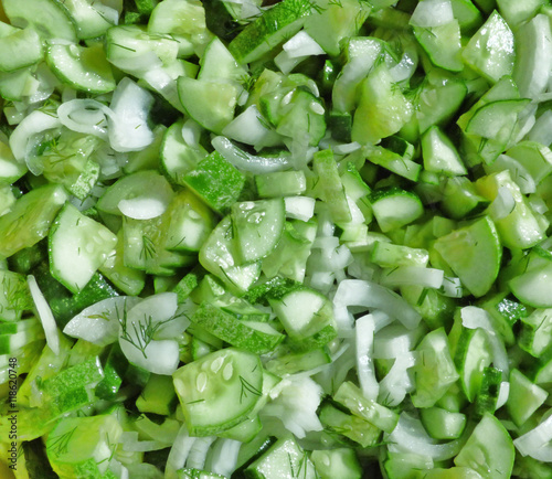 Green cucumbers and white onion in salad. Natural food texture. Vegetables background.