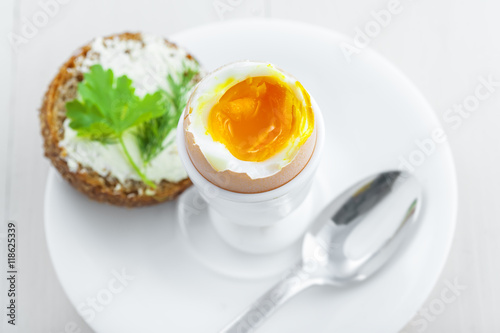 Perfect soft boiled egg, open bread sandwich with butter and cup of coffee on a table. Traditional food for healthy breakfast. Top view.