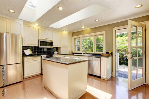 White kitchen with granite tops. Kitchen island and tile floor. © Iriana Shiyan