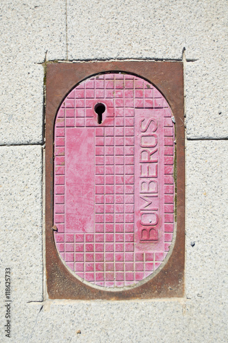 High angle detail of hydrant pink cover and rasty frame on granite sidewalk photo